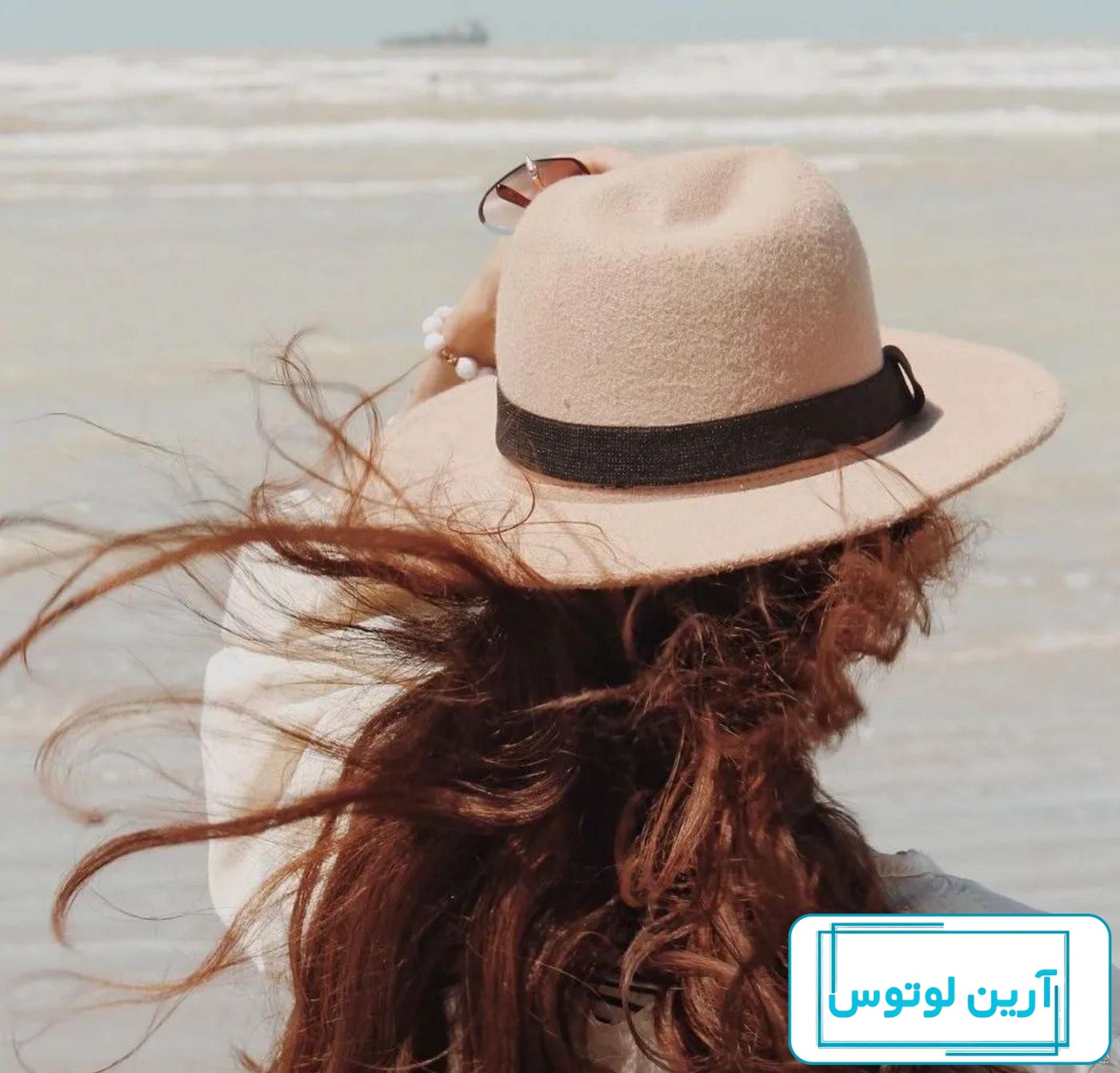 یک دختر در یک کلاه سفید و در لباس سیاه و سفید با یک شفت در استودیو در پس  زمینه سفید یک دختر با لب های قرمز و پوست صاف می ایستد